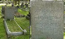 A granite headstone in the shade of a tree, surrounded by other gravestones