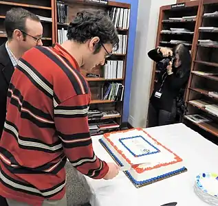 A man cuts into a slab cake.