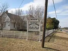 White painted house behind a sign announcing the Robert E. Howard Museum