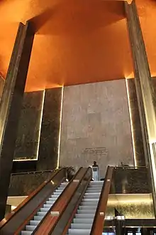 View of the International Building's lobby, looking up the escalators toward the mezzanine