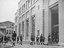 Photo of school boys carrying books into library