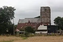 Stone building with square tower showing above smaller buildings.