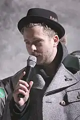 A color photograph of American musician Ryan Tedder performing live into a microphone.