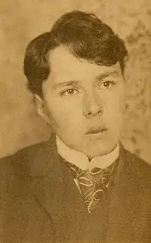 Sepia photograph of a woman with very short hair dressed in a man's suit and tie.