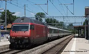 Red locomotive pulling coaches arrives at island platform