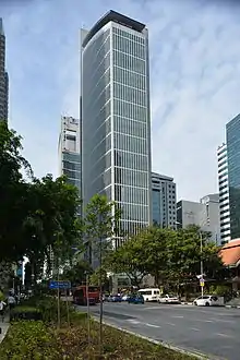 Ground-level view of a 30-storey building with a rounded, glass facade on one side and a straight-edged facade of concrete and windows on another; the concrete siding protrudes above the roofline