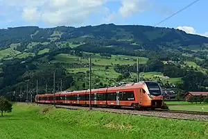 Copper-colored trainset in front of a green hill