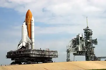 A crawler-transporter carrying  Discovery  (STS-114) travels the ramp to Launch Pad 39B. The vehicle's back end can be raised, keeping the Shuttle and the MLP level.