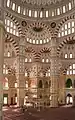 The interior of the mosque showing the symmetry of the mosque, the intricate artwork and calligraphy, and the decorative ablaq in the arches