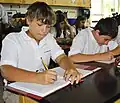 Middle School Life Science students jot down notes in their lab notebooks during a lecture.