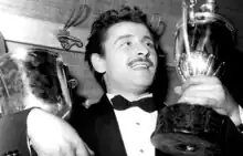 Black-and-white photograph of Domenico Modugno in 1959 holding two trophies.