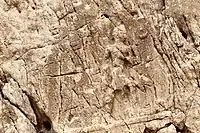 Sarpol-e Zahab, relief I. Beardless warrior with axe, trampling a foe. Sundisk above. A name "Zaba(zuna), son of ..." can be read. He is usually considered as a ruler of the Lullubi, but he could be a ruler of the Kingdom of Simurrum, son of Iddi(n)-Sin.