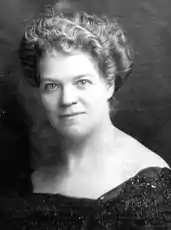 Portrait of a white woman with her light hair in a wavy bouffant updo.