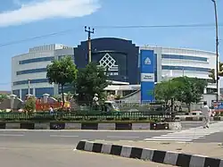 Front of large round building, with street and trees in front