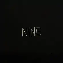 A black background with matchsticks spelling out "NINE" on it