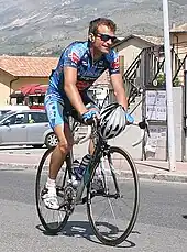 A cyclist riding while holding his helmet