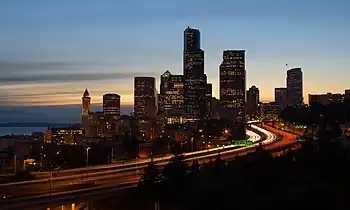 Skyline of city at dawn. A major highway winds itself into the downtown area.