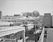 A monorail train departs from the covered south terminal as seen from a nearby rooftop.