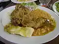 Kid stew accompanied by cooked yuccas, white rice, beans and Creole sauce