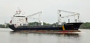 A blue and white tanker ship on river with shore in background