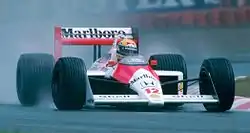 An orange and white F1 car being driven by Ayrton Senna