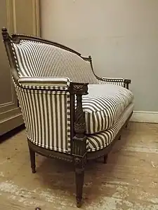 An antique settee reupholstered in ticking fabric.  Historically, ticking was not used to cover fine furniture.