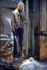 Grief-stricken woman in jacket and gloves, holding a flashlight