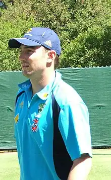 A man wearing a dark-blue shirt and navy or black trousers.