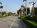 A street near vegetation, promotional posters, and streetlights, with zoo buildings in the background.