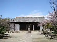 Low and wide wooden building with white walls.