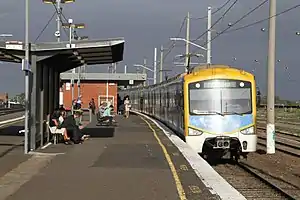 A modern train at a station that is falling apart