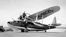 Flying boat fitted with landing wheels parked on solid ground