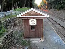 A small wooden shelter and a stone wall next to a railway line