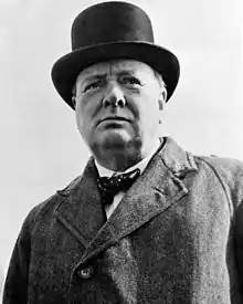 A close-up of Winston Churchill wearing a grey jacket and a bowler hat, looking upwards.