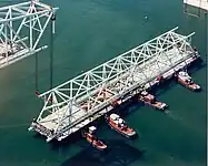 Main bridge span (secured on barge) being towed away