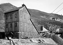 A black and white photograph of two wooden buildings, one closer to the camera than the other