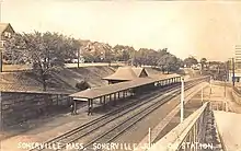 Postcard of a below-grade railway station with a small depot building