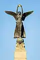Winged figure holding a golden crown at the top of the obelisk.
