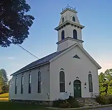 A white church with a rounded steeple and green door