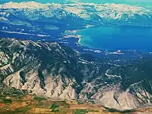 Aerial photo showing a mountain lake surrounded by mountains with a low gap in the foreground