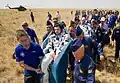 Support and medical personnel carry the crew to the medical tent.