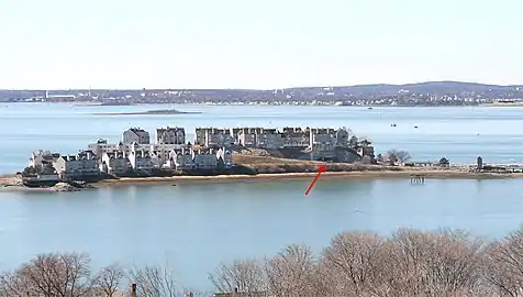 A 2010 view, looking westward at Hog Island, the site of Fort Duvall. Later the site was purchased, covered with condominiums, and renamed Spinnaker Island. The arrow points to the casemate of Gun 2 of Battery Long, which is now a parking garage.