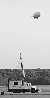 A modern blimp approaches its mobile mooring mast.