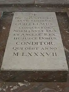 A stone slab on the ground with carved lettering on it