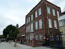 three-storey brick building with sandstone doorways, with a modern annex on the left