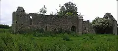 A ruined stone chapel in a field