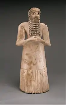 Standing male worshiper, one of the twelve statues in the Tell Asmar Hoard; 2900–2600 BC; gypsum alabaster, shell, black limestone and bitumen; 29.5 x 12.9 x 10 cm; Metropolitan Museum of Art