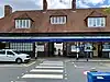 A brown-bricked building with four brown-bricked chimneys and a rectangular, dark blue sign reading "STANMORE STATION" in white letters