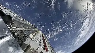 A batch of small satellites attached to the rocket with the Earth in the background