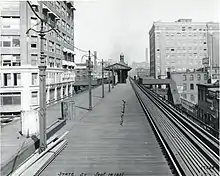 The platform of an elevated rapid transit station, with buildings on both sides